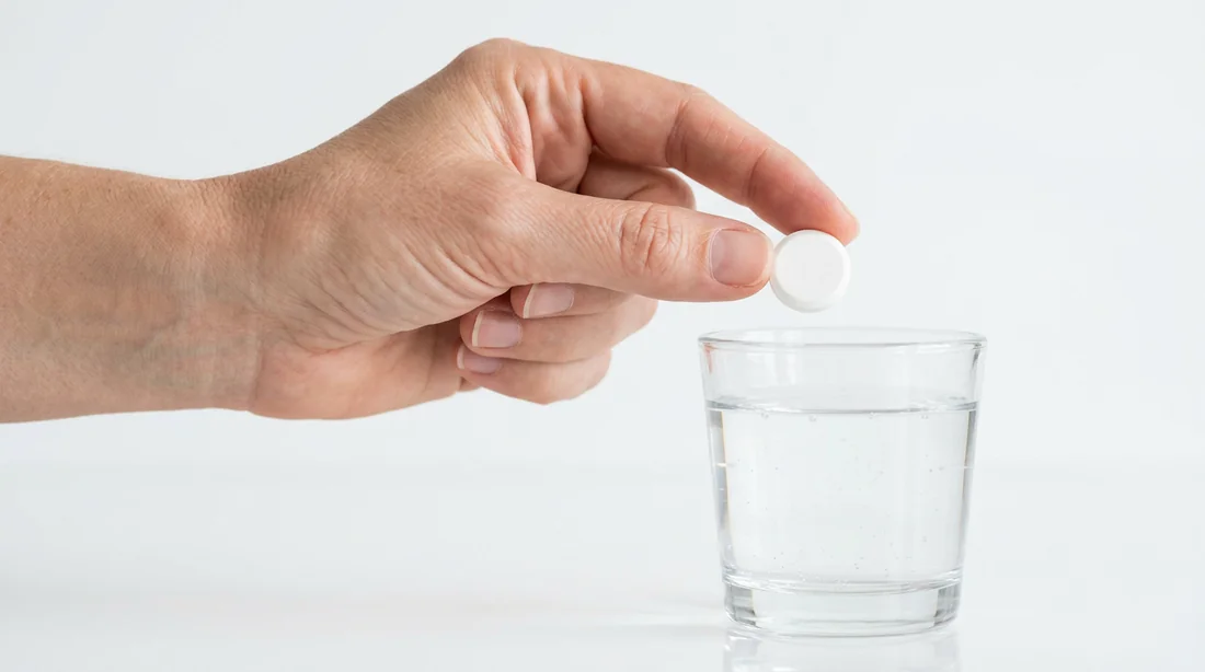 Gros plan sur un comprimé de paracétamol et un verre d'eau